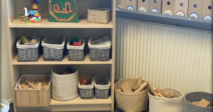 A traditional classroom cupboard with learning materials stacked on top of each other in different coloured plastic boxes